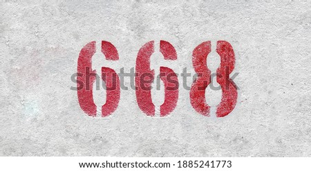 Red Number 668 on the white wall. Spray paint.