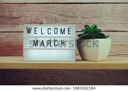 Welcome March word in light box on wooden shelves background