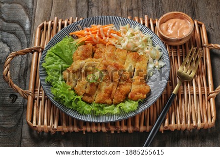 Chicken fillet or Chicken katsu in a plate served with mayo salad on a bamboo tray.