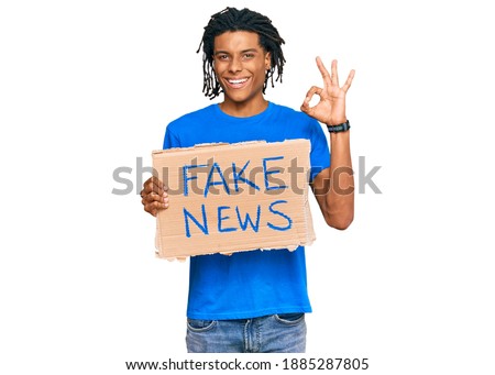 Young african american man holding fake news banner doing ok sign with fingers, smiling friendly gesturing excellent symbol 