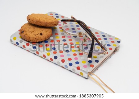 Oatmeal cookies and glasses lie on the spotted cover of the diary