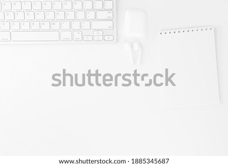 Workplace in the office with a white desk. Top view from above of keyboard with notebook,and headphones. Flat lay with copy space. Business and finance concept.
