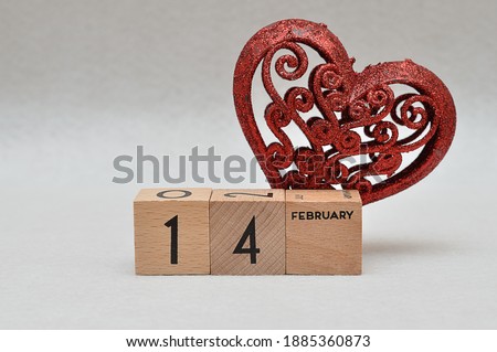A red decorative heart with 14 February on wooden blocks