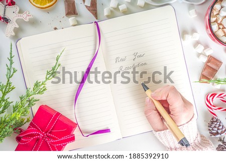 2021 Pandemic Year New Year Resolution Concept.  New Year Goals and Resolution background: notepad with new normal covid life goals, christmas decor, hot chocolate, white background flatly top view