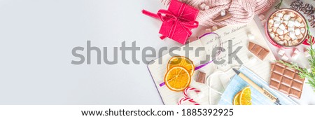2021 Pandemic Year New Year Resolution Concept.  New Year Goals and Resolution background: notepad with new normal covid life goals, christmas decor, hot chocolate, white background flatly top view