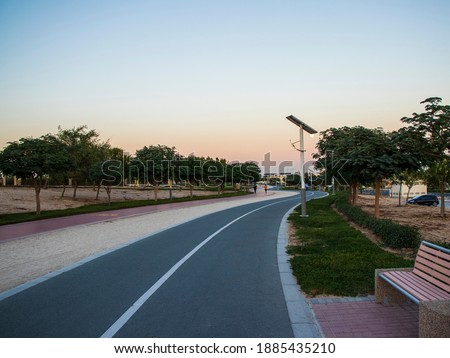 Jogging and cycling tracks in Al Warqa park, Dubai, UAE in the evening. Lamp post powered by solar panels can be seen in the picture.