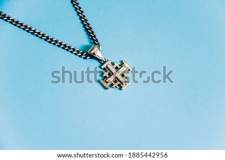 Jerusalem silver crusader cross with chain on a blue background.

