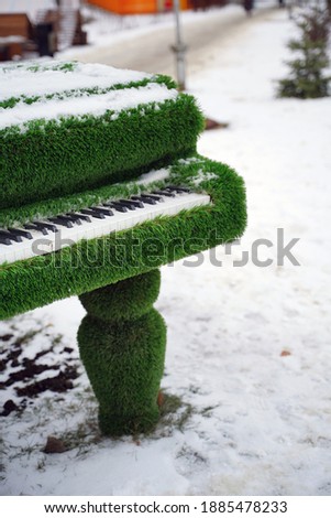 Close up of decorative piano on street in wintertime. Installation of green musical instrument with snow in winter season