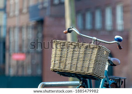 Selective focus of wicker baskets in front of bicycle handlebar parked on the street along the canal of Amsterdam, Netherlands land of bicycles, Cycling is a common mode of transport in Holland.