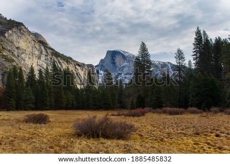 A view of clouds over Half Dome and mountains in Yosemite National Park, California from a hiking trail in Yosemite Valley.