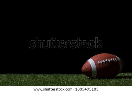 American football on green grass, on black background. Team sport concept