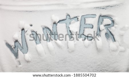 The inscription Winter, on the surface of the car hood, covered with snow