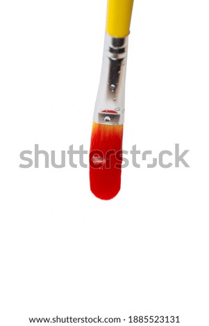 a paintbrush with a yellow handle makes a smear of red paint on a white background. copy space.