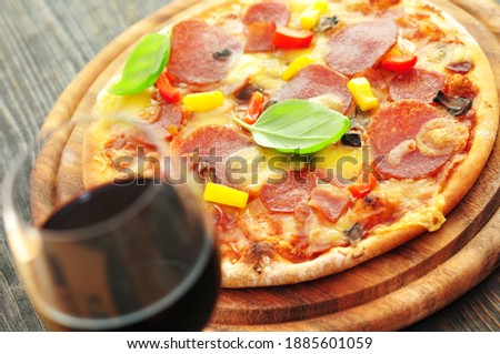 Pizza with salami and basil on wooden background, closeup.