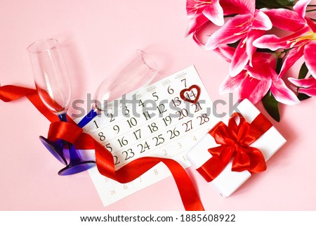 Valentine's day card. Calendar, gift box, lily flower and champagne glasses on a pink background. concept of holidays Valentine's Day, Mother's Day, Birthday.