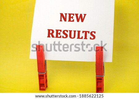 The new result is written on a white sheet that stands on two red clothespins on a yellow background. Concept photo