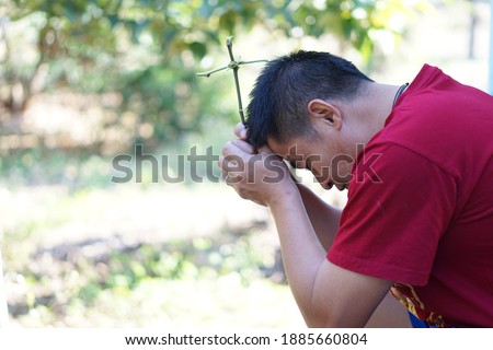 A Christian Asian man feels stressed and suffering from life problems. He is praying for the blessing of the God for a better solution to life. Concept for faith , Love in Jesus to all mankind