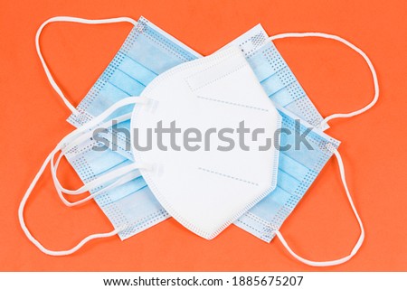 some surgical masks and a single particle filtering half mask isolated on orange background