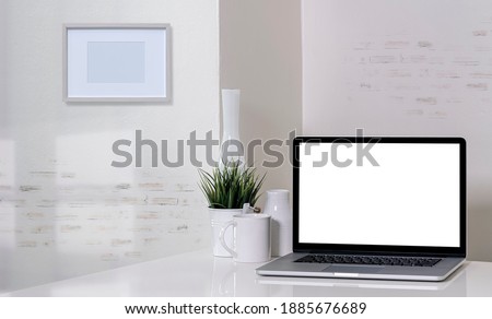 Mockup laptop computer and ceramic vase on white top table in modern room.