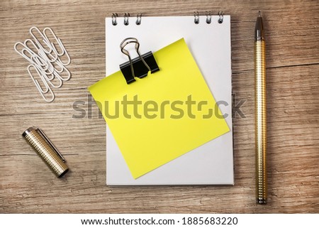 a yellow note on a white notebook with white paper clips and a yellow pen next to it. Concept photo