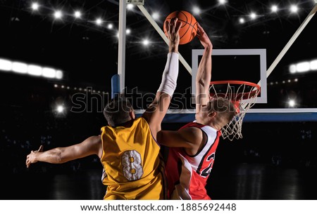 Two basketball players in action in arena. Blocked shot