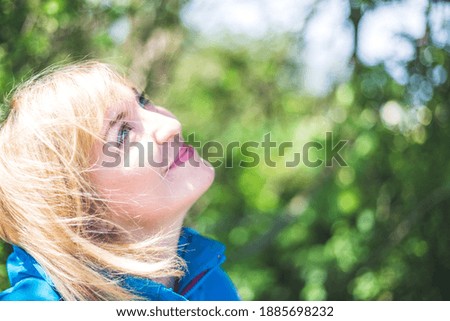 Portrait of attractive young girl outdoors, spring time, blurry green background