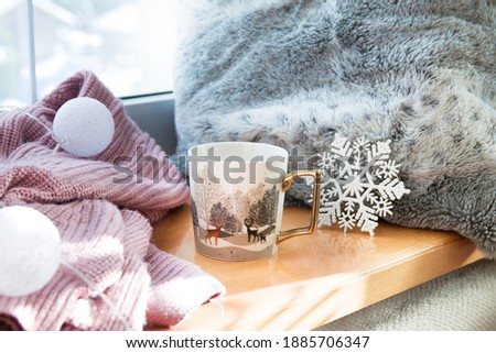 Gold and white winter cup in Deers with tea or coffee on the window sill by the sweater, winter decoration Royalty-Free Stock Photo #1885706347