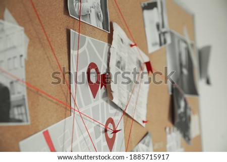 Detective board with crime scene photos and red threads, closeup