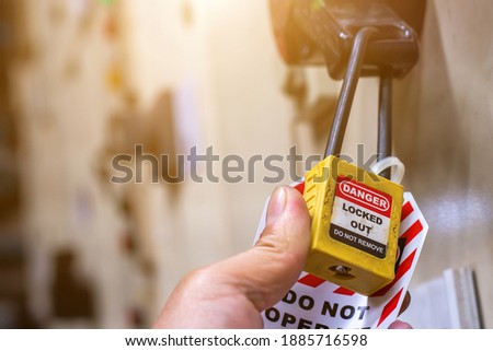 Hand holding yellow key lock and tag for process cut off electrical,the toggle tags number for electrical log out tag out
