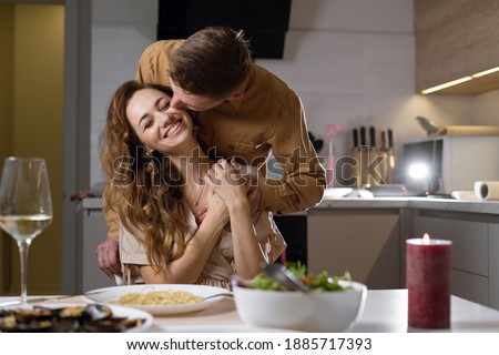 romantic dinner for two, married couple at the table with wine. A man kisses a woman on the neck. The concept of celebrating valentine's day, birthday, Royalty-Free Stock Photo #1885717393