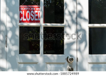Red closed sign hanging on the white entrance door of a business office, business concept