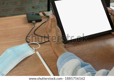 Medical mask and Digital tablet white blank screen display in  male hands on table  work form home