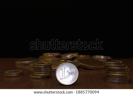 Selective focus on a one euro coin on black background with other currencies out of focus, trade and money concept