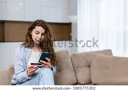 Portrait happy female shopper using instant easy mobile payments making purchase in online store young woman customer holding credit card and smartphone sitting on couch at home