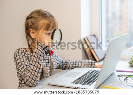 Little girl doing her homework at home and using a laptop