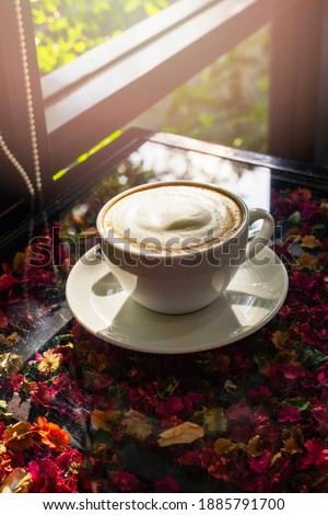 Coffee latte in a white mug on the table in the morning under the sun makes it delicious