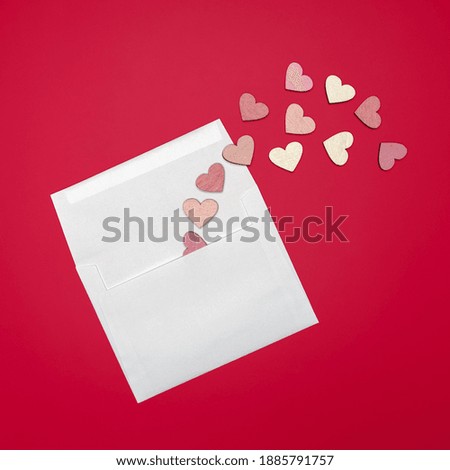 Creative flat lay of paper envelope with hearts around on bright red background. Love concept