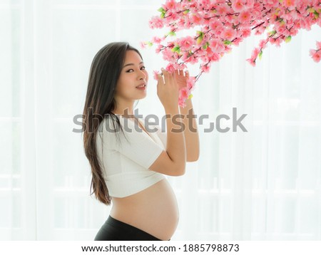 Pregnant beautiful woman Stand to holding flowers in a Japanese-style room and think about the day when you would happily meet your child