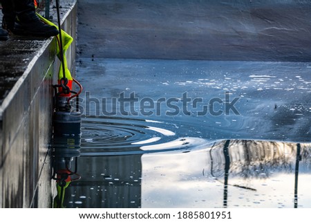Immersion of the drainage pump in a cesspool filled with contaminated water. close-up. Royalty-Free Stock Photo #1885801951