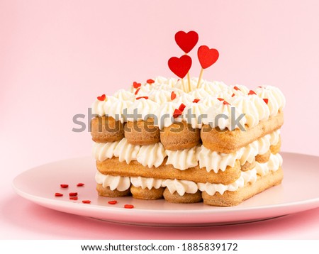 Saint Valentine's day dessert. Tiramisu with heart shaped decoration and red sprinkles. Pink paper background. 14 february concept.