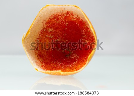 Dried granadilla peel painted with red oil paint on white background with reflexion - abstract composition and texture