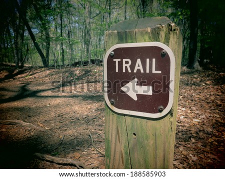 A filtered photo of a trail marker sign with an arrow pointing to the correct direction. Royalty-Free Stock Photo #188585903
