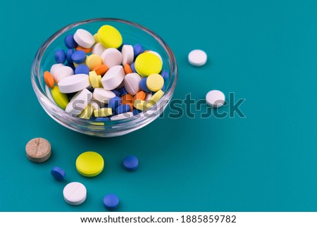 
Lots of pills in a glass bowl on a blue background.