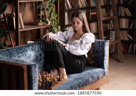 A girl plays chess with herself, a teenager studies chess moves, learning a professional game, chess and checkmate.
