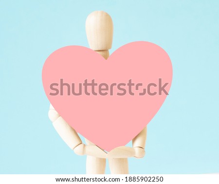 Wood Man Holding heart on cork board background Empty copy space for inscription or objects. Sign symbol idea, concept of love