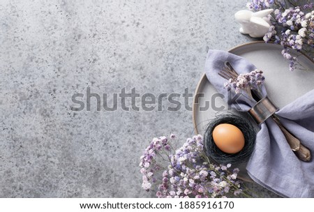 Easter table setting with violet decor on grey table. Elegance dinner. Top view. Space for text.