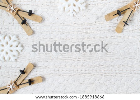 winter flat lay with skis and snowflakes on white knitted background.