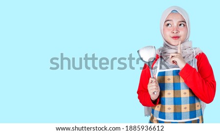 Asian hijab woman cooking woman isolated on blue background having doubts and thinking. free copyspace