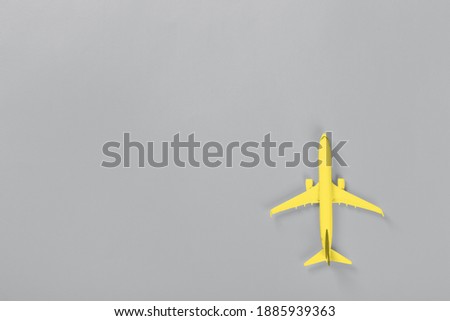 Yellow Model of passenger airplane on ultimate gray colored paper texture, flat lay