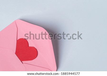 Minimal composition with a pink envelope with red heart inside for valentine day on light blue background. Copy space for text